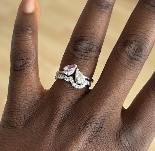 Hand wearing a platinum ring set with pink and clear gemstones.
