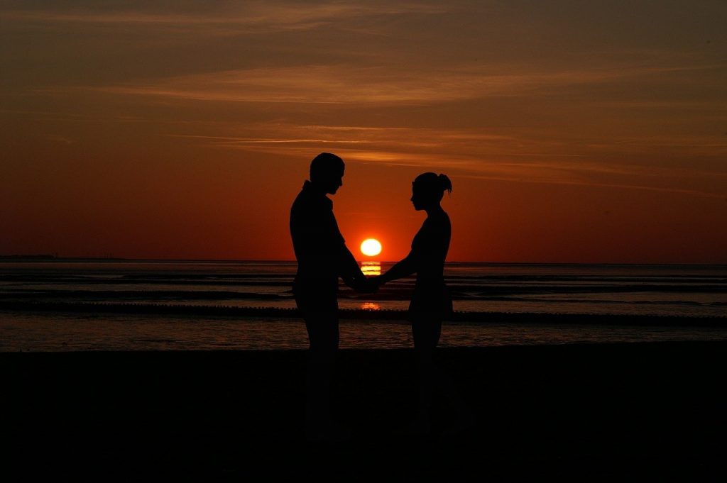 Couple holding hands at sunset on the beach