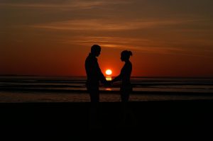 Couple holding hands at sunset on the beach
